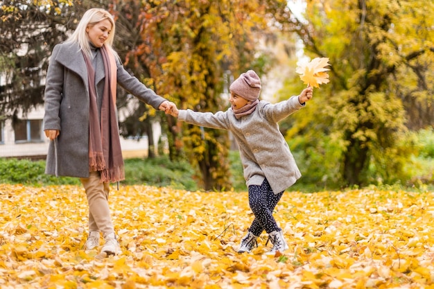 Happy family mother and child daughter play and laugh at the\
autumn walk. mother and child relations. fashionable mother and\
daughter in a stylish look with the same jackets