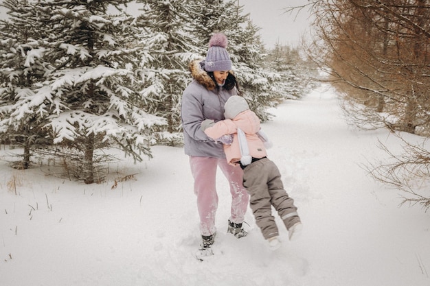 La famiglia felice madre e figlia si divertono a giocare durante la passeggiata invernale all'aperto. famiglia nella foresta d'inverno