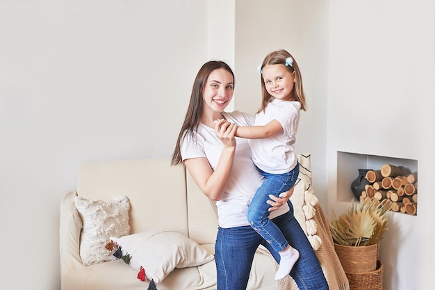 Happy family. Mother and daughter at home. Young woman and girl. Mothers and childrens day. Good morning and love concept. Light home interior.