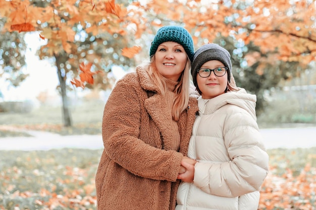 Happy family mother and daughter is in autumn city park They posing smiling playing and having fun Bright yellow trees