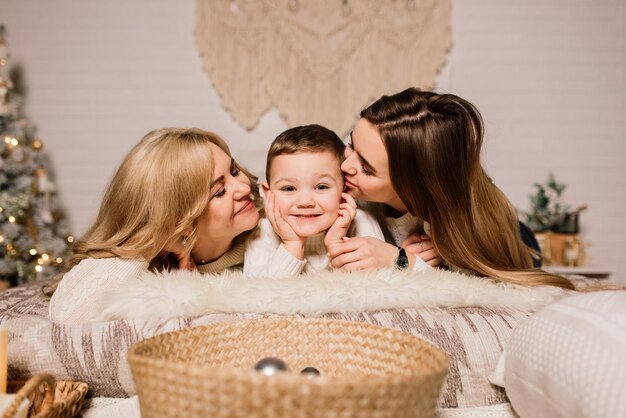 Happy family mother, daughter and son at christmas tree at home