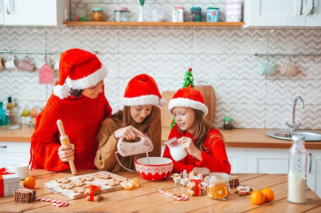 Happy family mother and daughters bake cookies for christmas