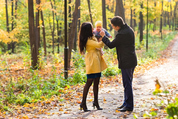 Famiglia felice di madre, padre e bambino nella natura autunnale