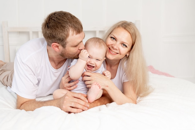 Happy family mother father and baby at home having fun, baby crawling in the foreground