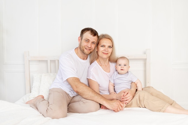 Happy family mother father and baby at home having fun, baby crawling in the foreground