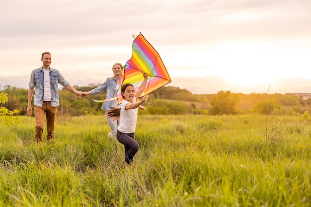 Happy family: mother, father, child daughter on nature on sunset.