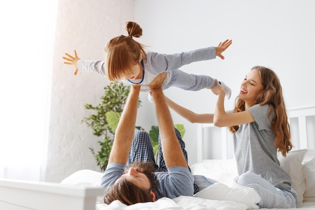 Happy family mother father and father child daughter in bed