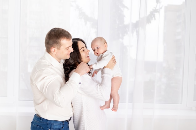 Happy family mother and father hold a newborn baby at home, the concept of happy loving family, lifestyle