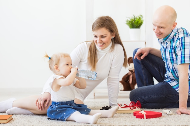 Happy family, mother, father and their baby together playing in living room at home. Children and