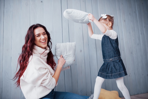 Happy family The mother and her child girl are fighting pillows. Happy family games