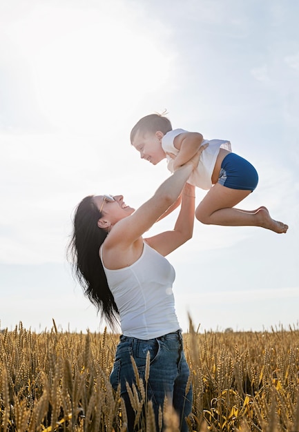 Happy family of mother and infant child walking on wheat field