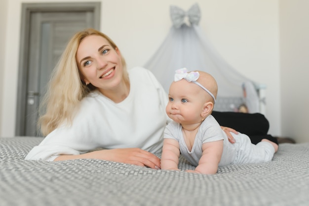 Happy family mother playing with newborn baby