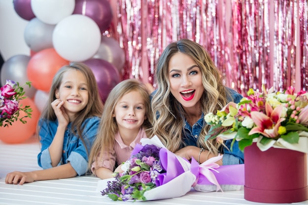 Счастливая семья, мать и две красивые девушки-дочери на празднике в цветах вместе