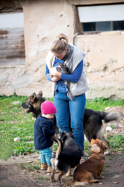 Foto famiglia felice-madre con figli abbracciando e nutrendo animali domestici cani gatti e capre in una fattoria di campagna