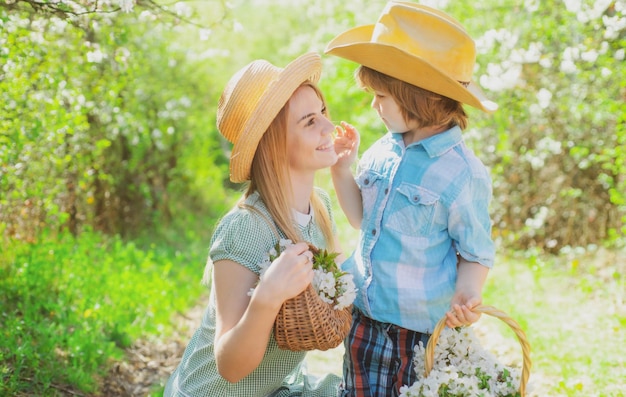 Happy family mother with son flowers at picnic Family mom with kid sitting on the grass in park