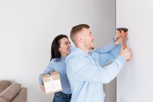 The happy family moved to a new apartment, the man hangs a picture on the wall