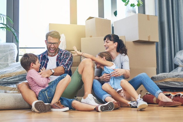 happy family and moving with boxes in apartment on the floor are excited with the mortgage parents children and new home for investment are playful with box in the living room of property