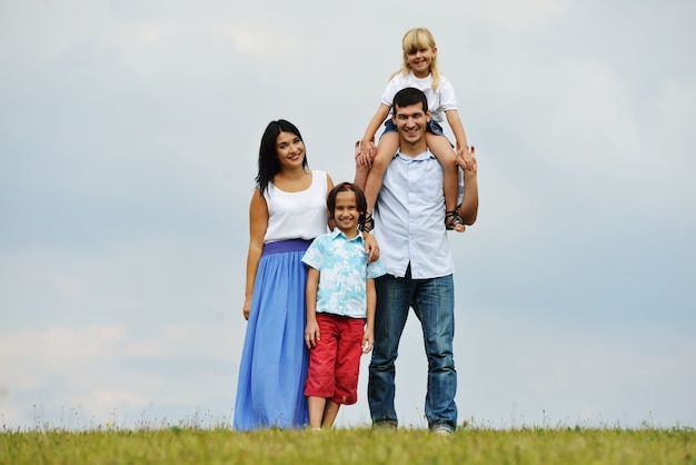 Happy family in nature walking on green summer meadow