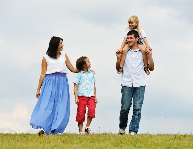 Happy family in nature walking on green summer meadow