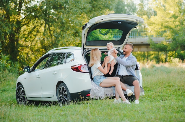 Happy family near car trunk on sunny day. Road trip