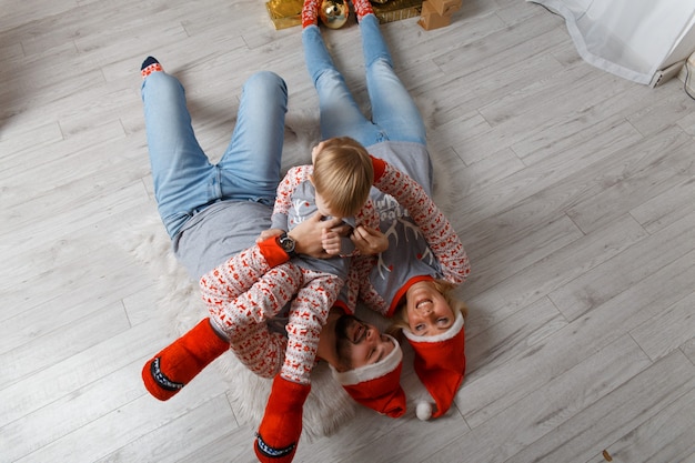 Happy family near christmas tree having fun on the floor.