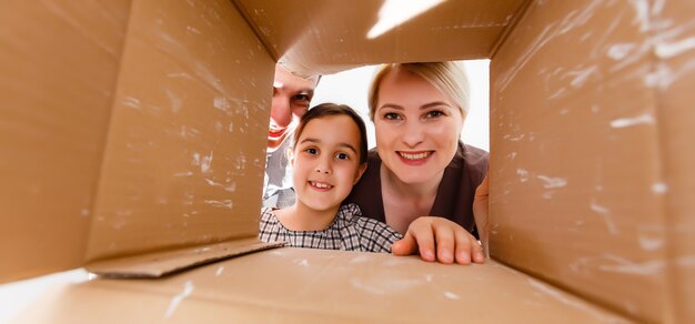 Happy family opening cardboard box - moving concept