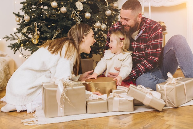 装飾された木の近くでクリスマスプレゼントを開ける幸せな家族