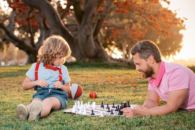 Счастливая семья на открытом воздухе отец и сын играют в шахматы в осеннем саду
