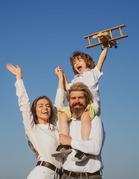 Happy family outdoor parents with child boy with toy airplane on fathers shoulders motherhood father