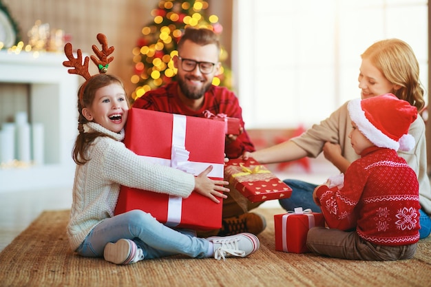 Foto i genitori e i bambini felici della famiglia aprono i regali la mattina di natale