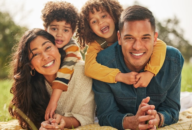 Happy family parents or couple with kids in a park together and happy for vacation or outdoor vacation picnic portrait and mother bonding with children and father in nature for summer travel