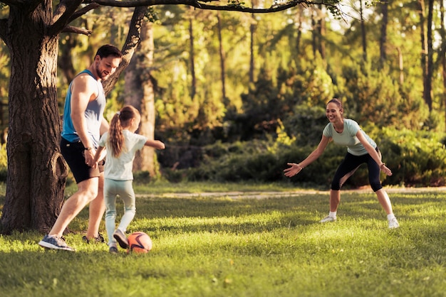 公園で幸せな家族がサッカーをしています。