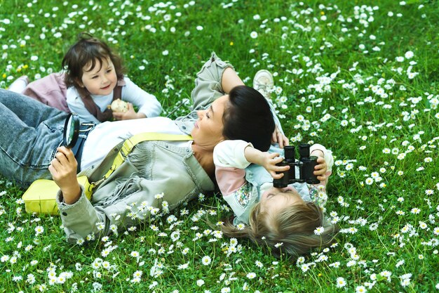 Счастливая семья в парке. Мать и ее две дочери, лежащие в поле ромашки.