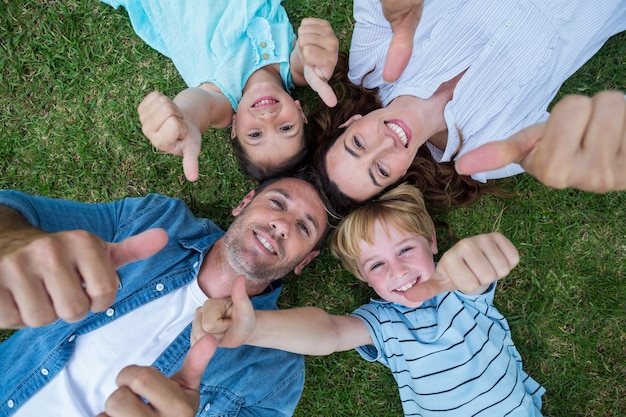 Happy family in the park together thumbs up on a sunny day