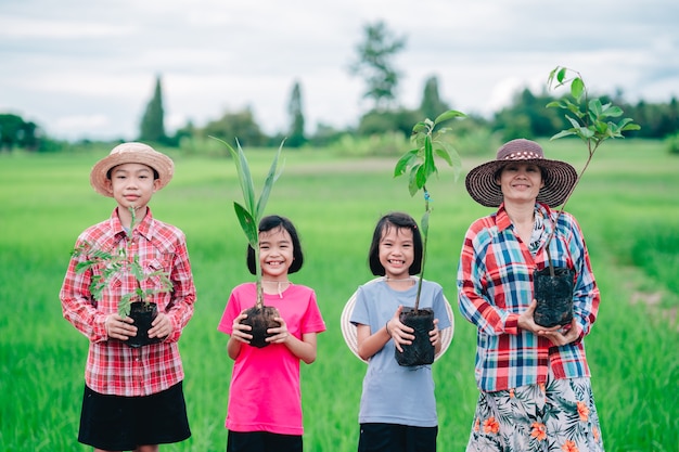 Happy family people holding seeding of tree for planting to garden on organic green rice field