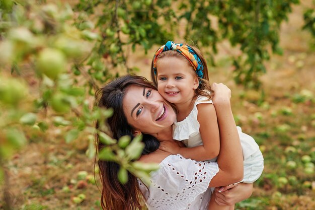 Mele felici di raccolto della famiglia sul giardino. madre e figlia nel meleto