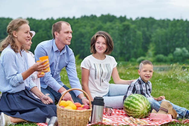 Famiglia felice a un picnic picnic nel prato o nel parco giovani amici ei loro bambini nella natura