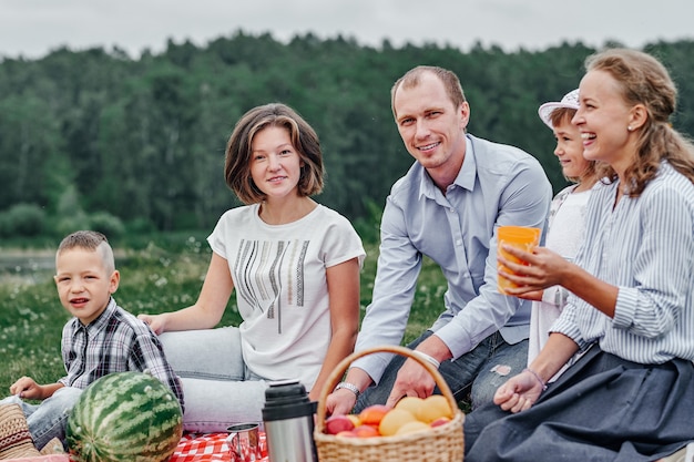 Happy family at a picnic. Picnic in the meadow or park. Young friends and their children in nature.