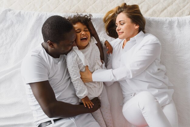 Famiglia felice che gioca a letto con la figlia