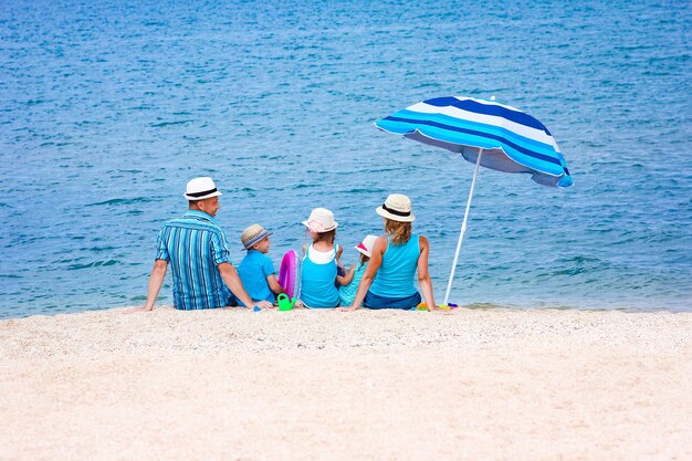 Счастливая семья, играющая на берегу моря на фоне песка