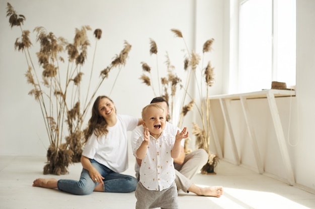 Happy family playing at home with their child on a white background with reeds