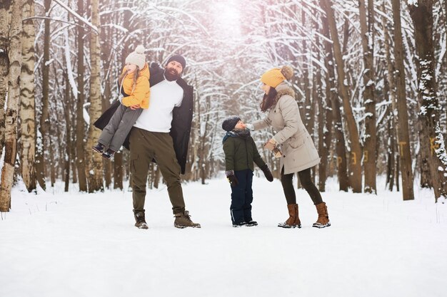 Happy family playing and laughing in winter outdoors in the snow. City park winter day.