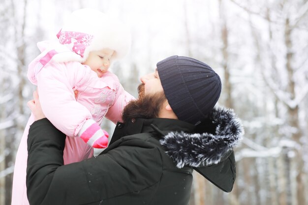 Happy family playing and laughing in winter outdoors in the snow. City park winter day.