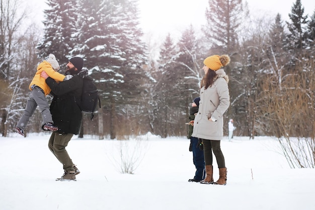 Famiglia felice che gioca e ride in inverno all'aperto nella neve. giornata invernale del parco cittadino.