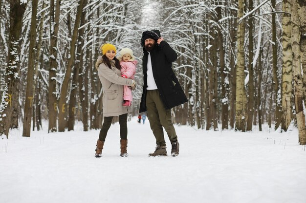 Famiglia felice che gioca e ride in inverno all'aperto nella neve. giornata invernale del parco cittadino.