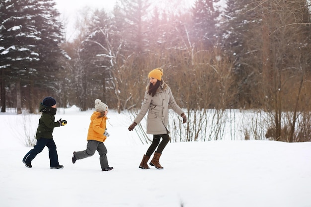 雪の中で屋外で冬に遊んで笑って幸せな家族。都市公園の冬の日。
