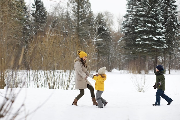 Happy family playing and laughing in winter outdoors in the snow. City park winter day.