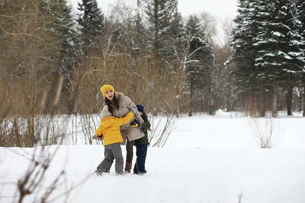 Happy family playing and laughing in winter outdoors in the snow. City park winter day.