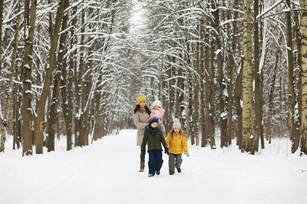 雪の中で屋外で冬に遊んだり笑ったりする幸せな家族。シティパークの冬の日。