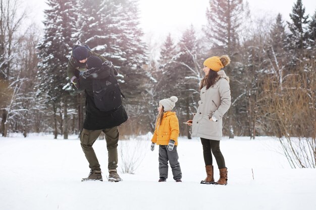 Happy family playing and laughing in winter outdoors in the snow. City park winter day.